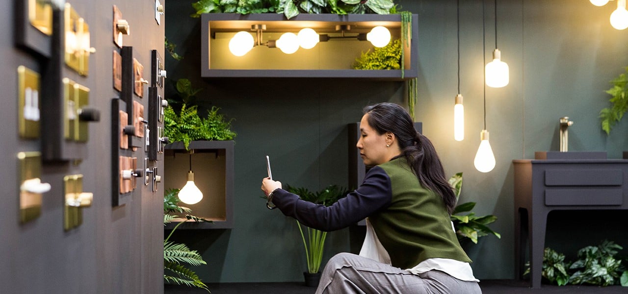 A visitor photographing the Dowsing and Reynolds lighting designs at the designjunction show